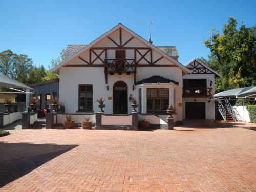 a large white house with a brick driveway at The Oak Potch Guesthouse in Potchefstroom