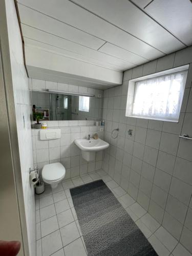 a white bathroom with a sink and a toilet at Schöne Ferienwohnung in ruhiger Lage in Tuningen