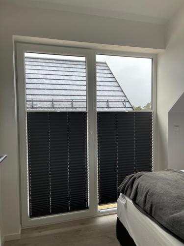 a bedroom with two large windows with blinds at Hytte på Sørlandet - Søgne in Søgne