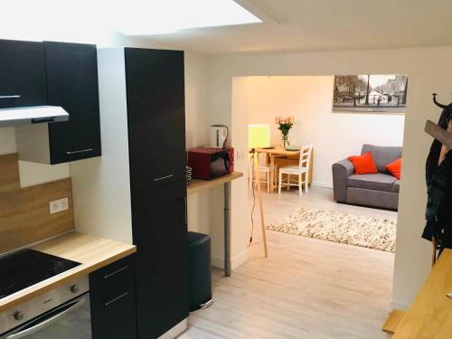 a kitchen with black cabinets and a living room at Chaleureux et spacieux appartement de centre-ville - Lit King Size - NETFLIX in Cherbourg en Cotentin