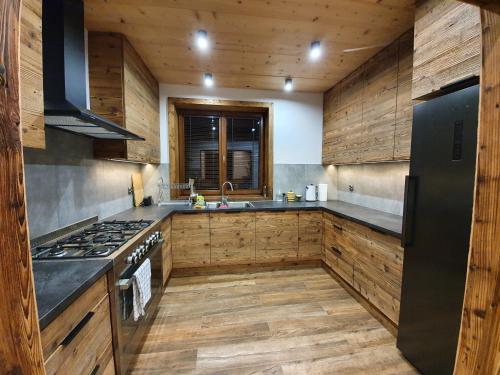 a kitchen with wooden cabinets and a black refrigerator at Wilcza Dolina in Sękowa