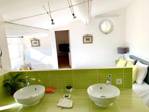 a bathroom with two white sinks and a green tile floor at La Maison du Courtil, Amande-Olive in Moustiers-Sainte-Marie