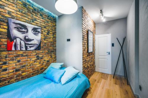 a bedroom with a brick wall and a blue bed at Apartament Przy Żurawiu in Gdańsk