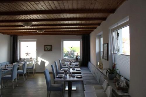 una sala da pranzo con tavoli, sedie e finestre di Hotel Pension Norddeich a Norddeich