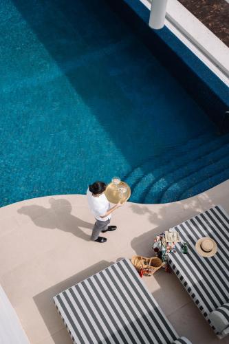 a man holding a sombrero standing next to a swimming pool at The Raintree, St. Mary’s Road in Chennai