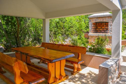 una mesa de madera y un banco en un porche con chimenea en SEA VIEW apartments en Klenovica