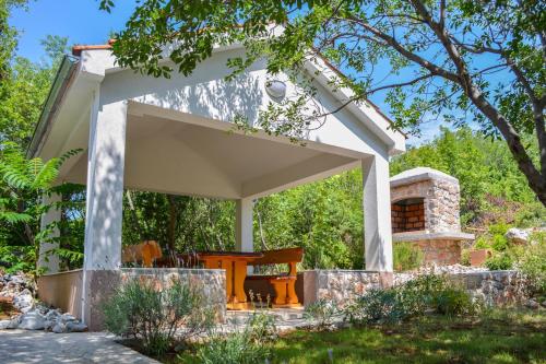 un pabellón con una mesa y una chimenea en un jardín en SEA VIEW apartments, en Klenovica