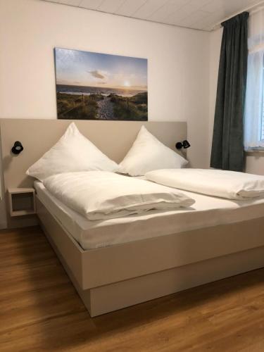 ノルトダイヒにあるpension-seegartenの壁に絵画が飾られたベッドルーム1室(ベッド2台付)