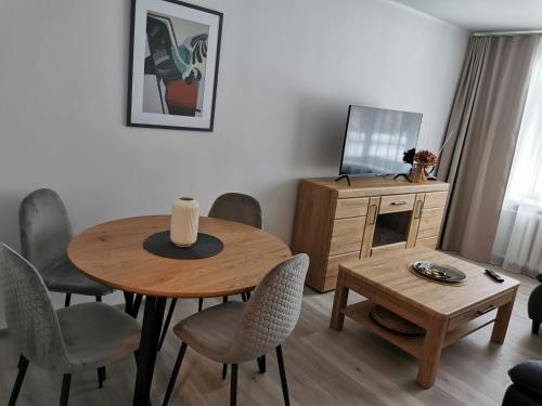 un soggiorno con tavolo, sedie e TV di Adelės apartamentai a Druskininkai