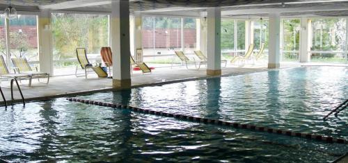 a large swimming pool with chairs in a building at Ferienwohnung, Monteurwohnung in Scheidegg
