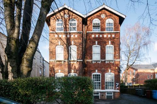 a tall brick building with white windows on a street at Benoît Apartments in Manchester