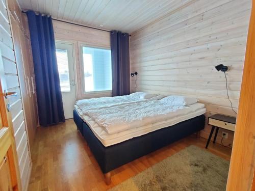 ein Schlafzimmer mit einem Bett in einer Holzwand in der Unterkunft Panorama Blue Apartments in Kilpisjärvi