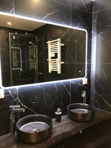 La salle de bains noire est pourvue d'un lavabo et d'un miroir. dans l'établissement Paisible et charmant T2 face à la mer, à Binic