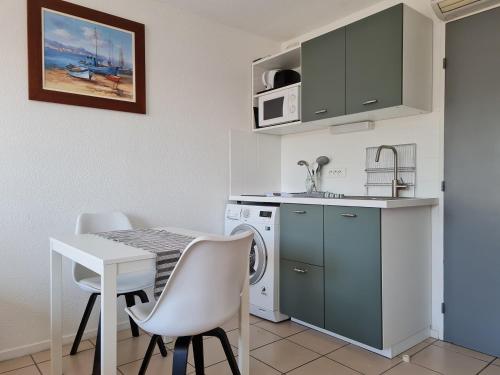 a kitchen with a table and a sink and a microwave at Studio climatisé 1 à 4 personnes vue mer in Le Grau-du-Roi