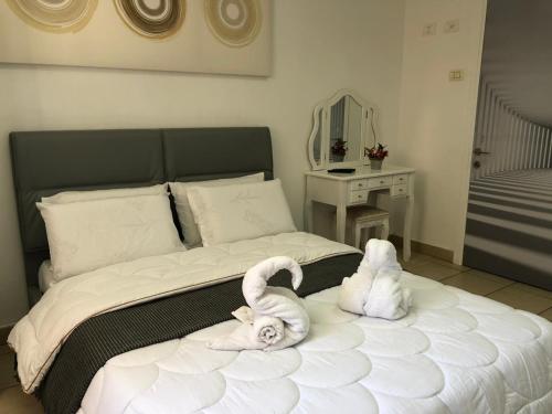 a bed with two swans laying on it at Sea Line Hotel From R&A Group in Bat Yam