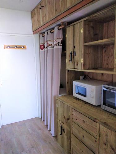 a kitchen with wooden cabinets and a microwave at Haut Alpin Superdévoluy in Superdevoluy