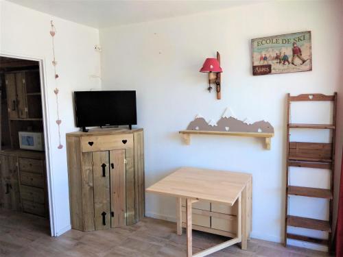 een kamer met een tafel en een tv aan de muur bij Haut Alpin Superdévoluy in Superdevoluy