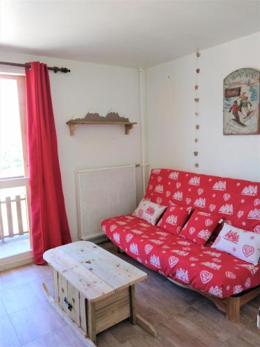a living room with a red couch and a table at Haut Alpin Superdévoluy in Superdevoluy