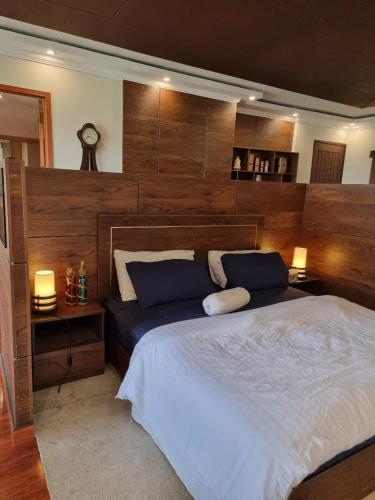 a bedroom with a large bed with a large wooden headboard at The Polo Residence, Lahore, Near Allama Iqbal International Airport (Apartment) in Lahore