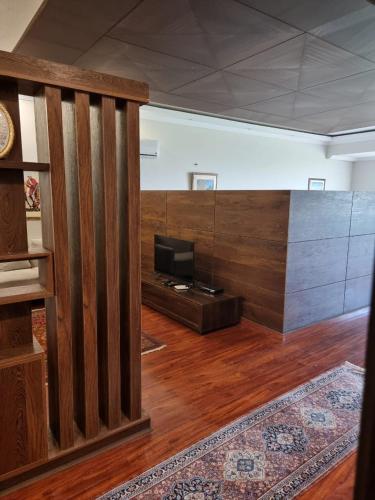 a living room with a tv and a wooden wall at The Polo Residence, Lahore, Near Allama Iqbal International Airport (Apartment) in Lahore