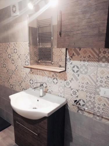 a bathroom with a sink and a mirror at La Taverna Appartamento Scala a Chiocciola in Follonica