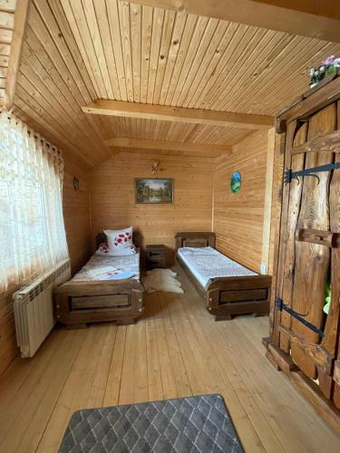 a room with two beds in a wooden cabin at Вілла в Карпатах in Vorokhta