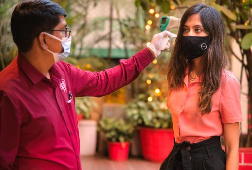 a man taking a picture of a woman wearing a mask at Hotel Oriental Aster - Mumbai International Airport in Mumbai