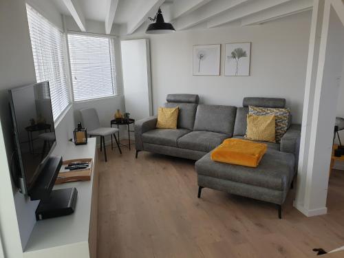 a living room with a couch and a tv at Duinengolf 5 in Middelkerke