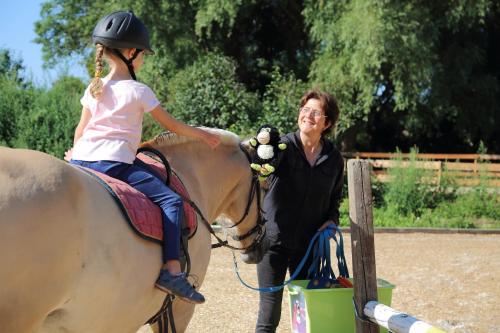 a woman teaching a girl to ride a horse at Hotel Gutshaus Kajahn in Gustow