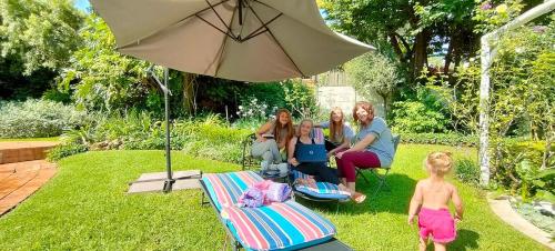 un grupo de personas sentadas en un césped bajo un paraguas en Libra Lodge, en Sandton