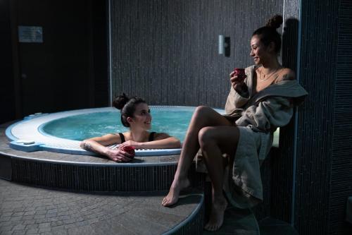 two women sitting in a hot tub in a room at Residence Hotel Serenella in Aprica