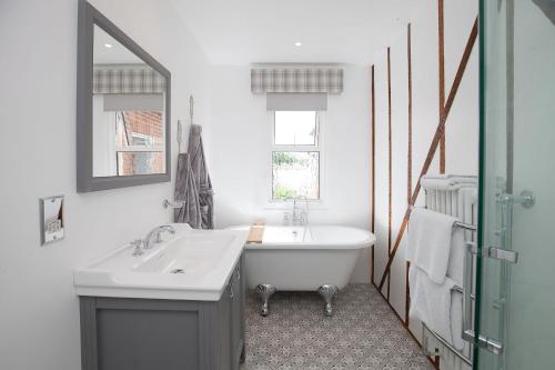 y baño con bañera, lavabo y espejo. en The Old House Guest House en Salisbury