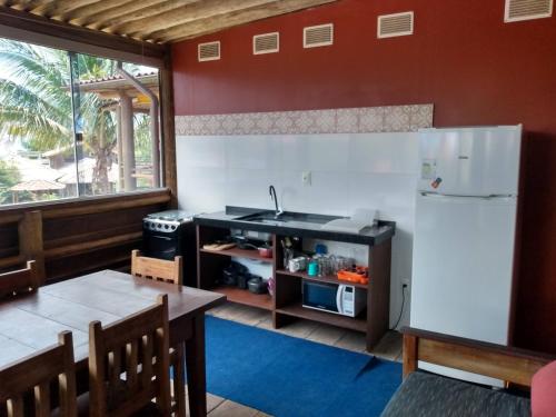 a kitchen with a white refrigerator and a table at Condominio Aldeia da Praia in Garopaba