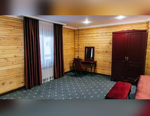 a room with wooden walls and a desk with a red chair at Eco Hotel Tan Tengri in Kostanay