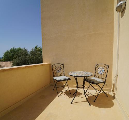 two chairs and a table on a balcony at Life Hotels Kalaonda Resort in Siracusa