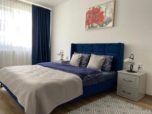 a bedroom with a blue bed and a window at Napoca Apartament in Floreşti