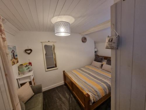 ein kleines Schlafzimmer mit einem Bett und einem Spiegel in der Unterkunft Pet friendly two bedroom cosy cottage in Tanygrisiau