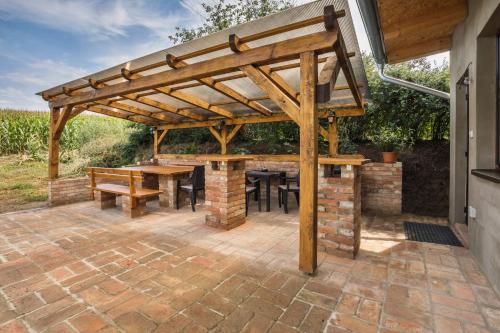 a wooden pergola on a patio with a table and chairs at Vinoza - ubytování a vinný sklep v Moravském Toskánsku in Hovorany