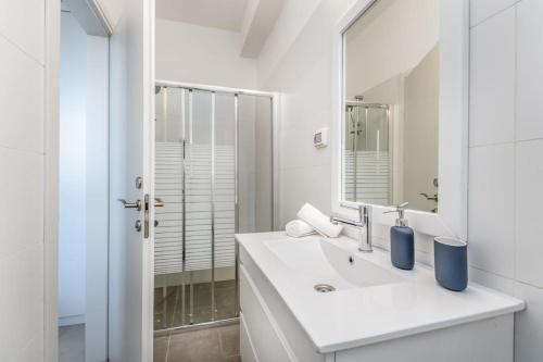 ein weißes Badezimmer mit einem Waschbecken und einem Spiegel in der Unterkunft garden apartments swimming over the lake in Tiberias