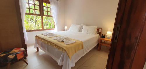 a bedroom with a large white bed with a window at Flat - SERRA E MAR - Paraty in Paraty