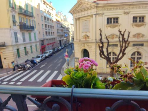 a view from a balcony with flowers on a city street at Hôtel Parisien in Nice