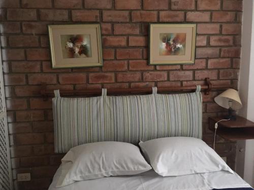 a brick wall with two pictures above a bed at Bungalows Cerro Azul in Cerro Azul
