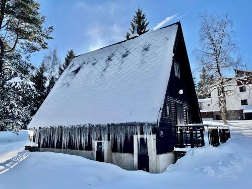 a black barn with snow on the side of it at Hotel a Penzion PEGAS in Nové Město na Moravě