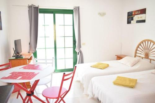 a room with two beds and a table and a window at Caleta Paraiso Sea View 137 in Costa de Antigua