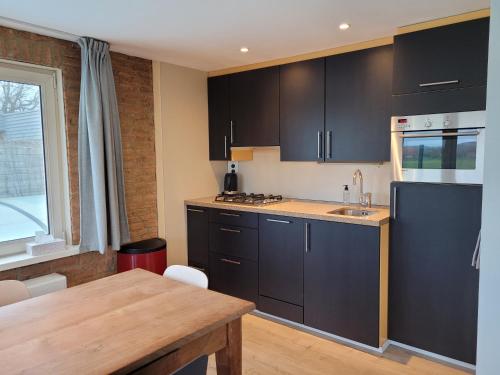 a kitchen with black cabinets and a wooden table at Zoet & Zout in Zoutelande
