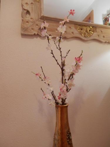 un vaso con fiori rosa di fronte a uno specchio di Acogedor Apartamento En Huesca a Huesca