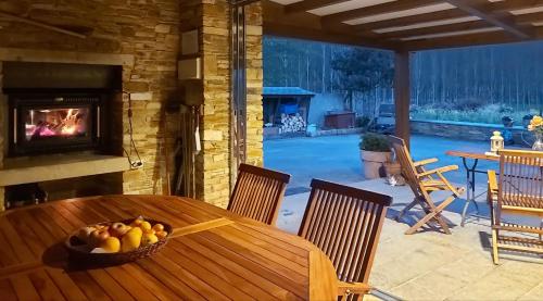 a wooden table with a bowl of fruit in front of a fireplace at Casetón do Forno. in Lourenzá