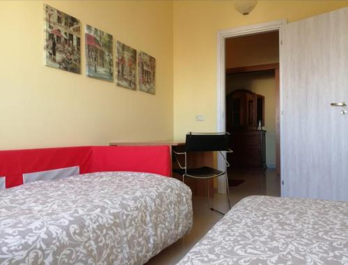 um quarto com uma cama vermelha e uma secretária com um computador em "La casa di Mariagrazia" Appartamento 4 locali em Sammichele di Bari