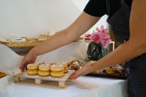 a person reaching for a tray of donuts on a table at Life Hotels Kalaonda Resort in Siracusa