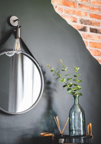 a mirror on a table next to a vase with a plant at The Hideaway Retreat in Omagh